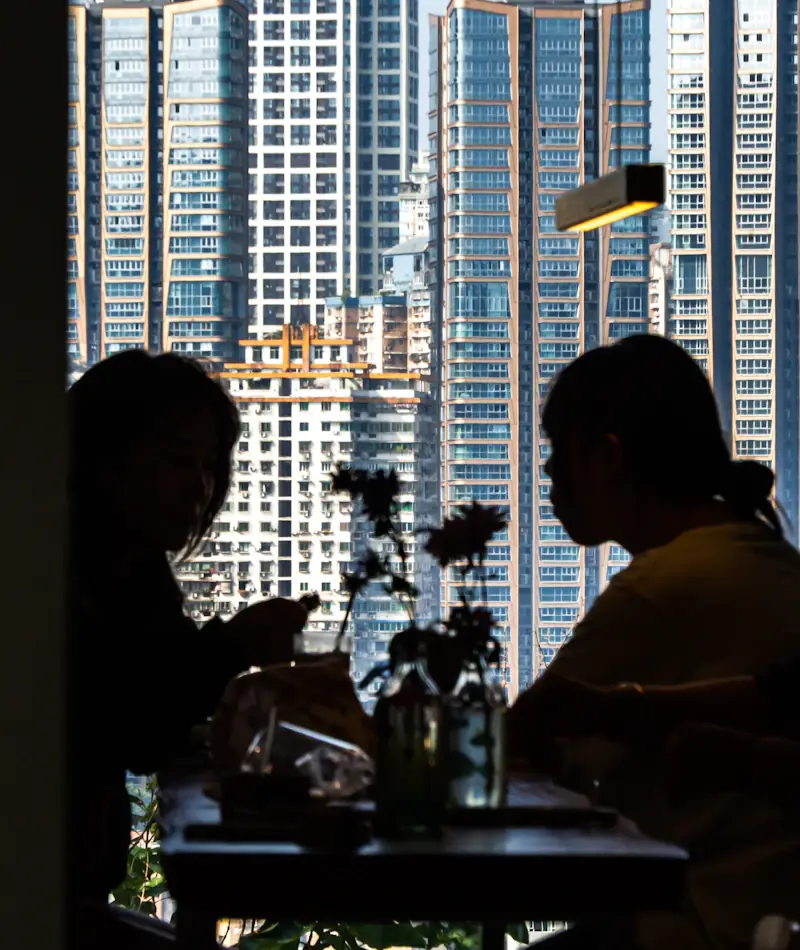 A couple talking beside a high window with the Chicago skyline behind them