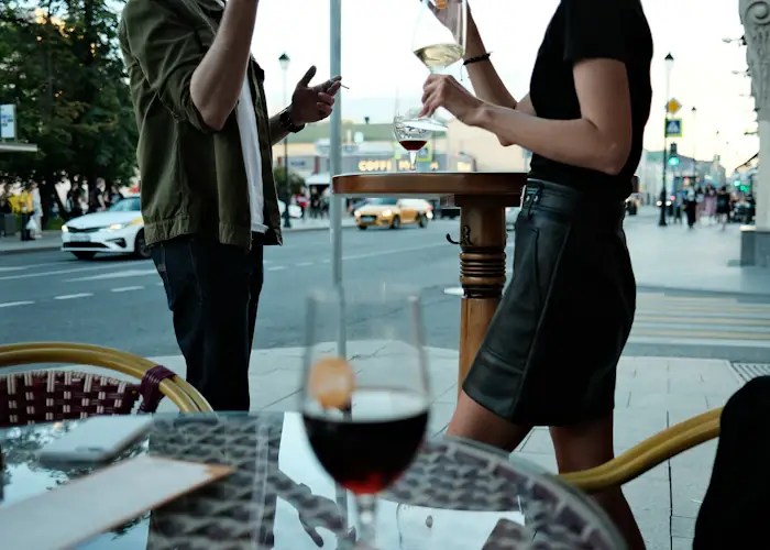Two people sharing a glass of wine across a restaurant table