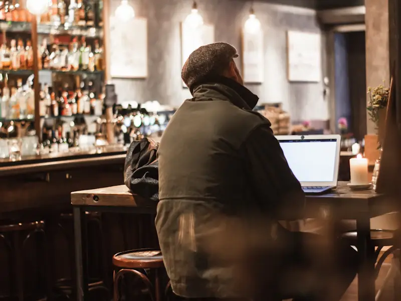 Man seated alone at a dimly lit Chicago bar with a drink in front of him