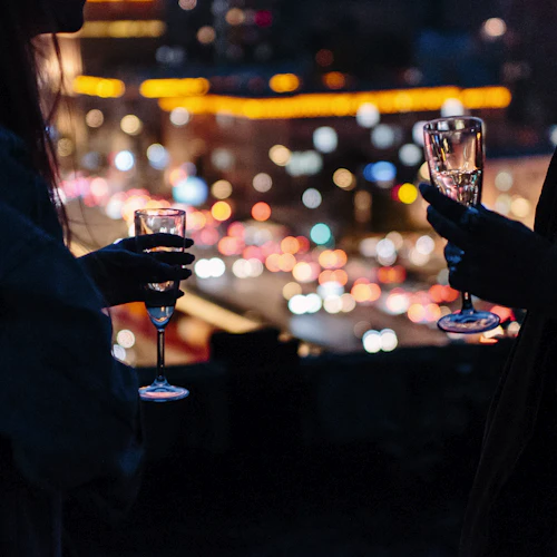 A woman holding a cocktail in a warmly lit bar